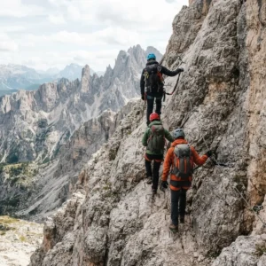 Grupo de personas con casco, de espaldas, en una vía ferrata de roca caliza